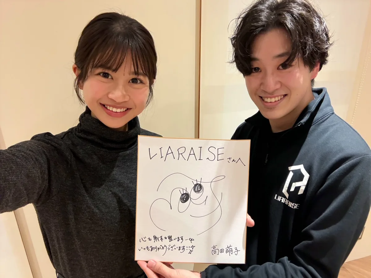 「心も身体も整います いつもありがとうございます!!」と書かれた色紙を持つ高田萌子さんと野田